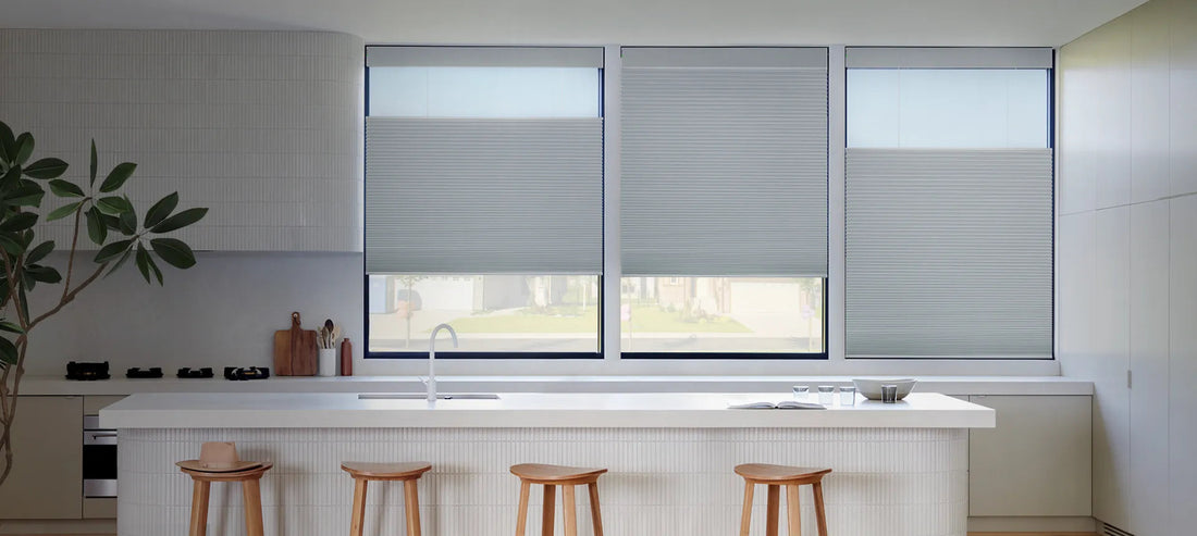 Gray cordless cellular honeycomb shades installed on three kitchen windows, showing clean inside mount installation with natural light filtering through the fabric