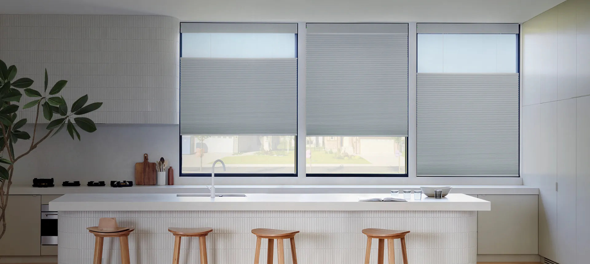 Gray cordless cellular honeycomb shades installed on three kitchen windows, showing clean inside mount installation with natural light filtering through the fabric