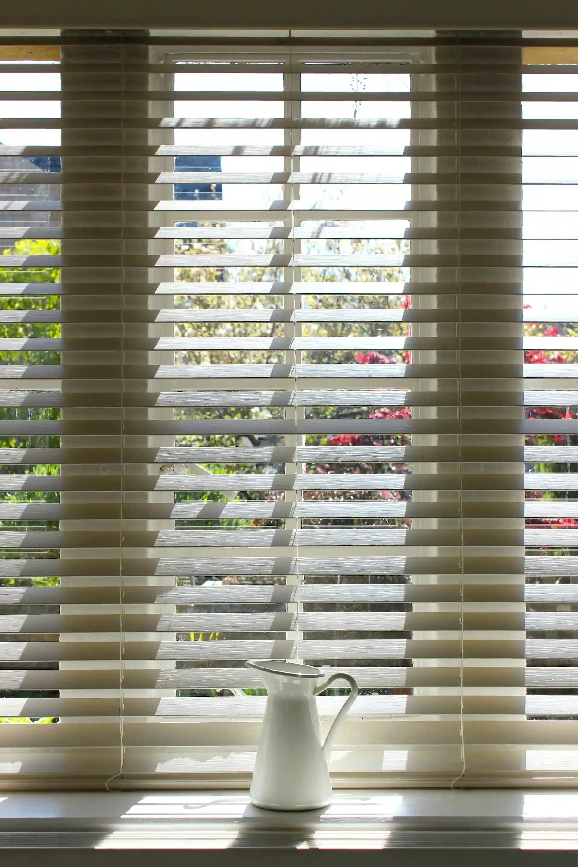 2 inch faux wood blinds on a sunlit window — natural light filtering through wood-grain slats