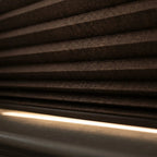 Close up of dark blackout honeycomb cellular shade fabric with insulating air pocket chambers and light block rail
