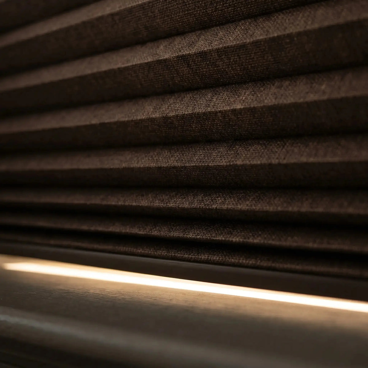 Close up of dark blackout honeycomb cellular shade fabric with insulating air pocket chambers and light block rail

