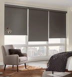 Three cordless dark charcoal blackout roller shades covering large bedroom windows with city skyline view
